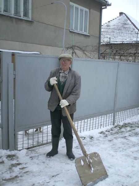 88-летний Юрий Росул убирает снег возле ворот. Он самый старый житель села