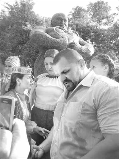 Тяжелоатлет Василий Вирастюк фотографируется возле памятника Ивану Фирцаку в селе Билкы