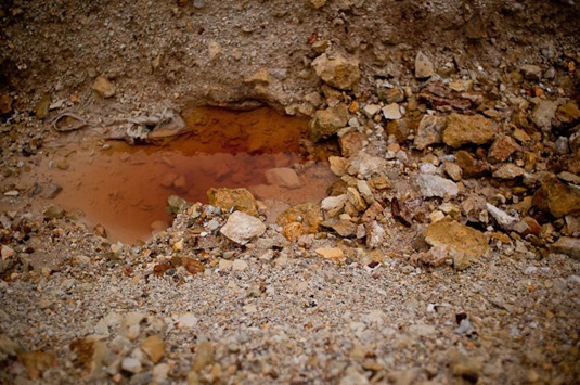 Все лужи вокруг рудника рыжие - воду окрашивают окисленные металлы, содержащиеся в горной породе